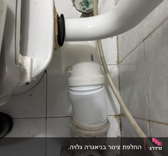 צינור לבן מחובר לאסלה בחדר אמבטיה